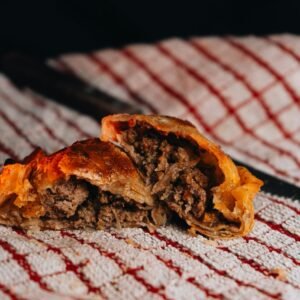 Close-up of a meat-filled Argentine empanada on a textured cloth, showcasing local culinary traditions.