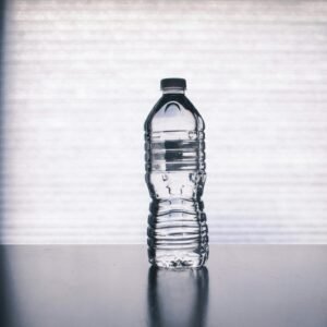 Stylish photo of a clear plastic water bottle on a reflective surface with a soft shadow.