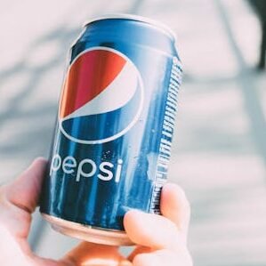 Refreshing Pepsi can held in hand on a sunny day. Perfect for advertisements.